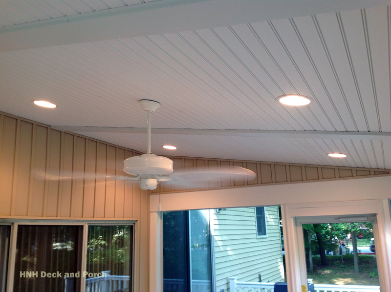 Screened-in porch with recessed lighting and fan.