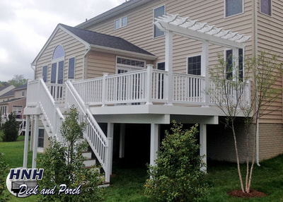Trex Transcend composite deck using Spiced Rum with a white vinyl railing, balusters, and pergola.