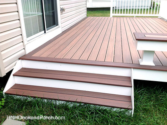 Vinyl patio deck with wide steps using Wolf PVC Decking Amberwood flooring and Rosewood border.