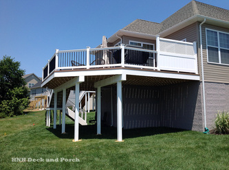 Vinyl deck using Wolf Tropical Hardwoods Collection PVC Decking with Amberwood flooring, Longevity white PVC railing with black round aluminum balusters and white privacy panel.