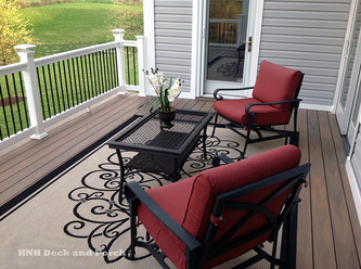 Vinyl deck using Wolf Tropical Hardwoods Collection PVC Decking with Amberwood flooring and white railing with black round aluminum balusters.