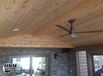 Screened porch with cedar ceiling, recessed lights, fan, and Versetta Stone wall.