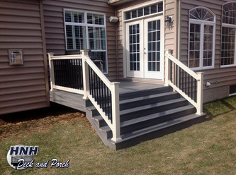 Composite wide steps with Trex Transcend Island Mist flooring with Almond PVC railing and black aluminum balusters.
