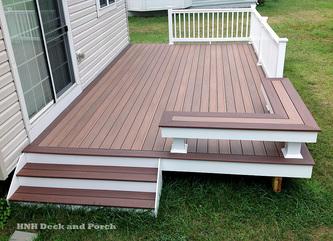 Vinyl patio deck using Wolf Tropical Hardwoods Collection PVC Decking with Amberwood flooring and Rosewood border and Longevity white PVC railing.