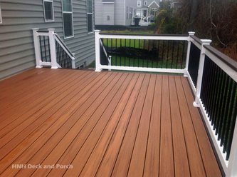 Composite deck using Trex Transcend Decking with Tiki Torch and Spiced Rum flooring and cap rail with black square aluminum balusters.