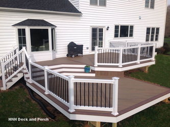 Vinyl deck with steps using Wolf Tropical Hardwoods Collection PVC Decking with Amberwood flooring and Rosewood border, white PVC railing with black square aluminum balusters.
