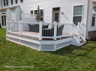 Vinyl deck with Wolf Home Products PVC Decking Amberwood flooring, Longevity white PVC railing and white round aluminum balusters, lattice, and privacy panel.